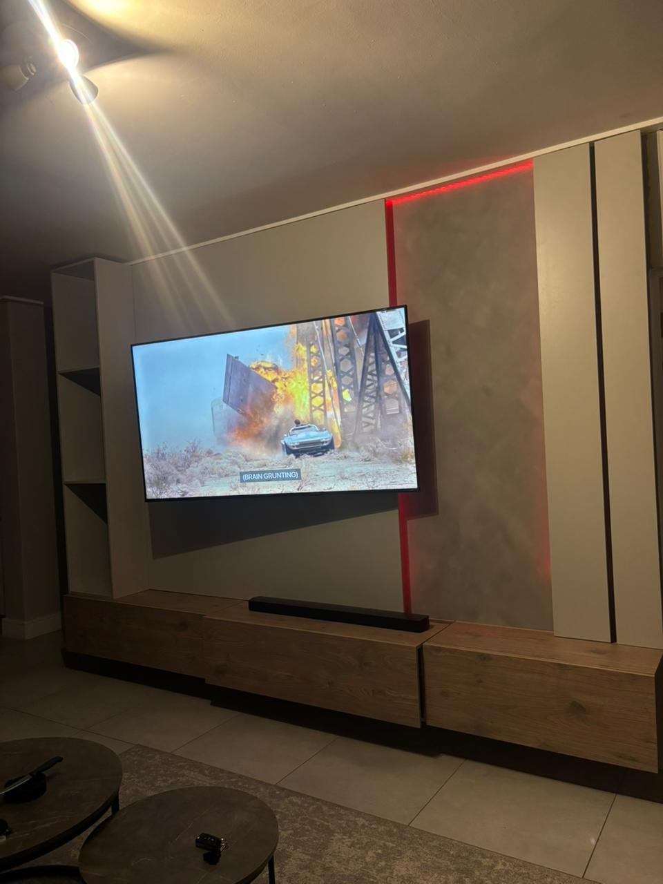 Wide view of media wall lounge with red LED backlight and oak floating console